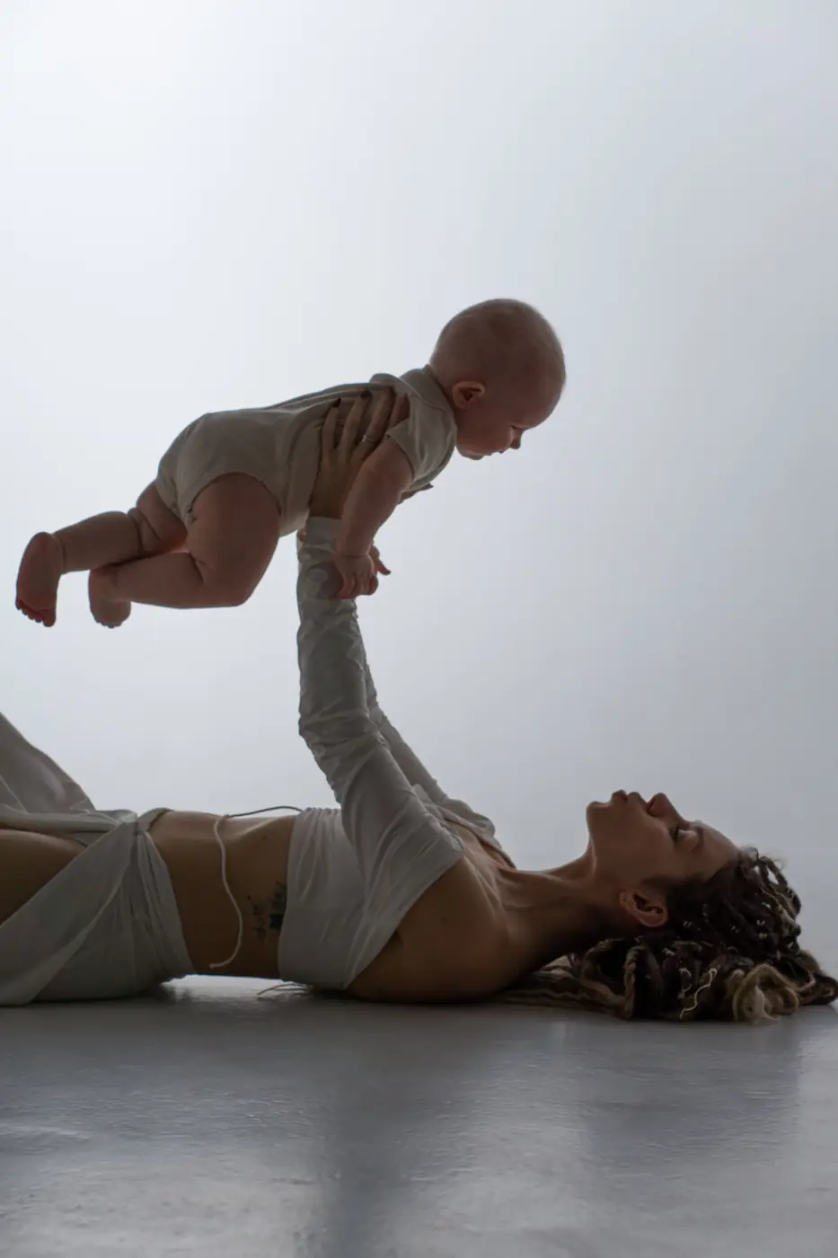 A mother holding her swaddled newborn close in warm light